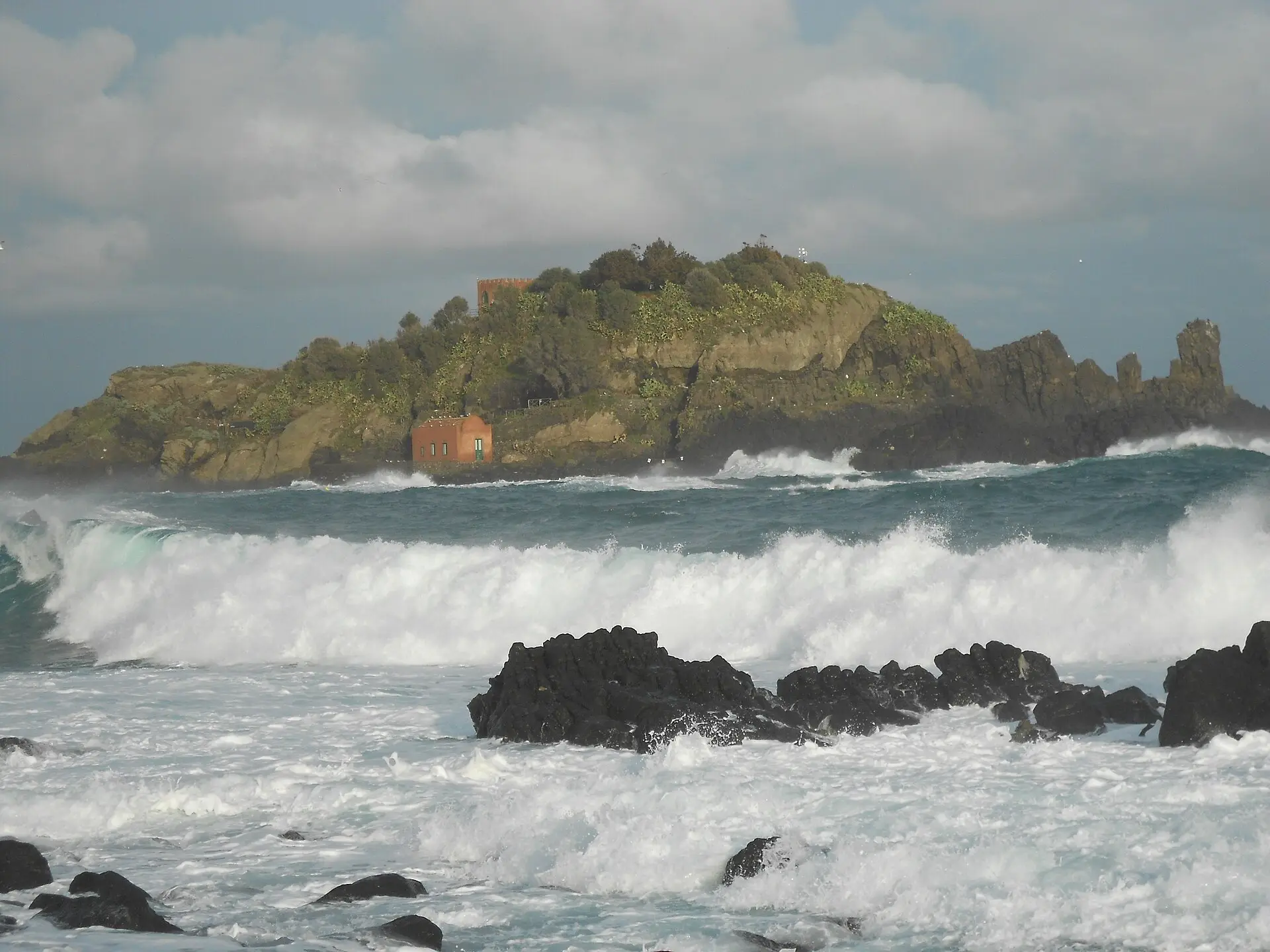 Isola Lachea, a small rocky island off Aci Trezza, seen across blue water