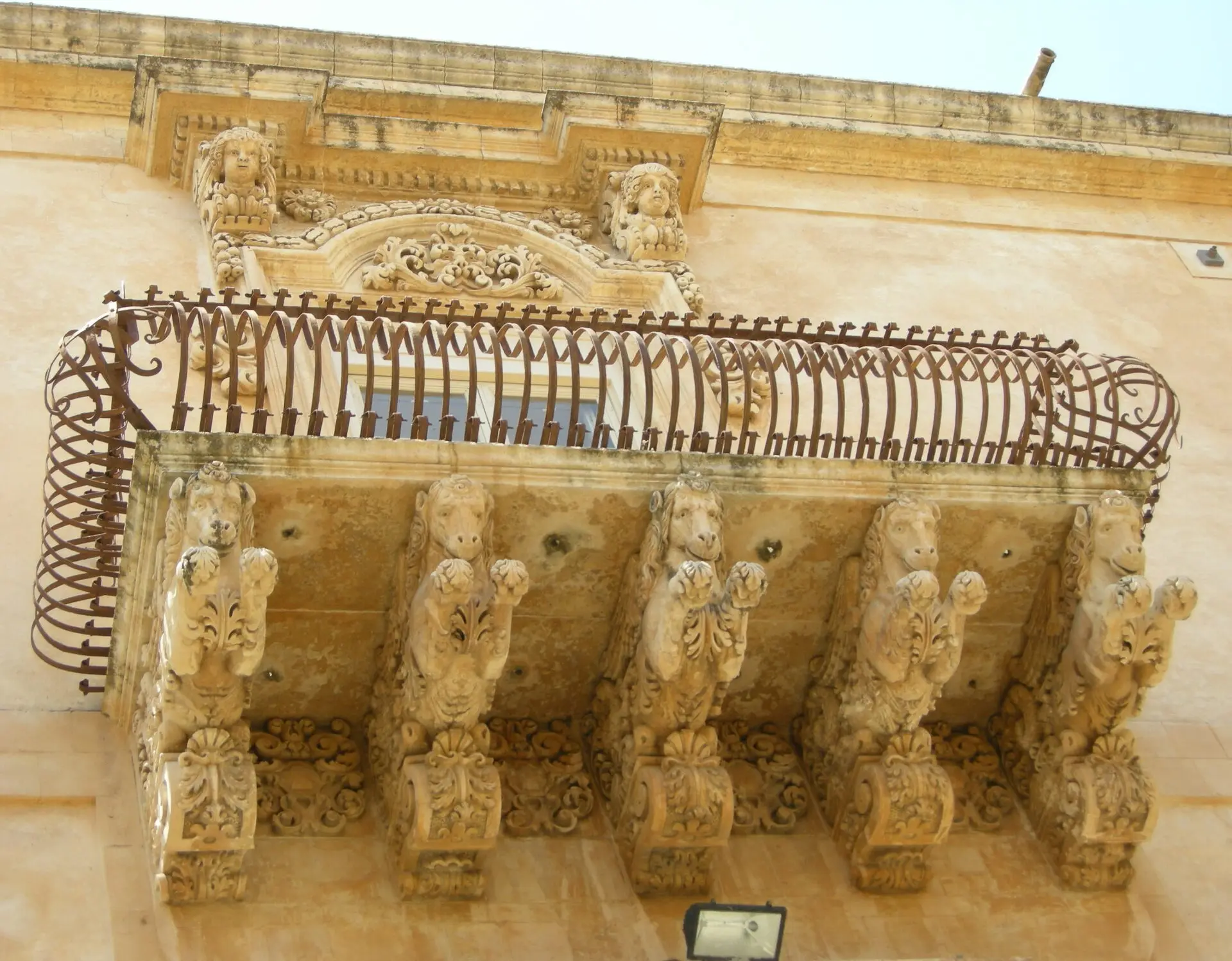 A carved stone balcony of Palazzo Nicolaci in Noto supported by rearing horses